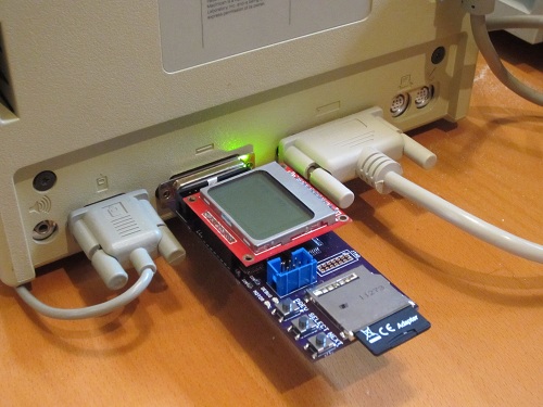 A Macintosh Floppy Emu plugged into the external drive port of a vintage Mac.